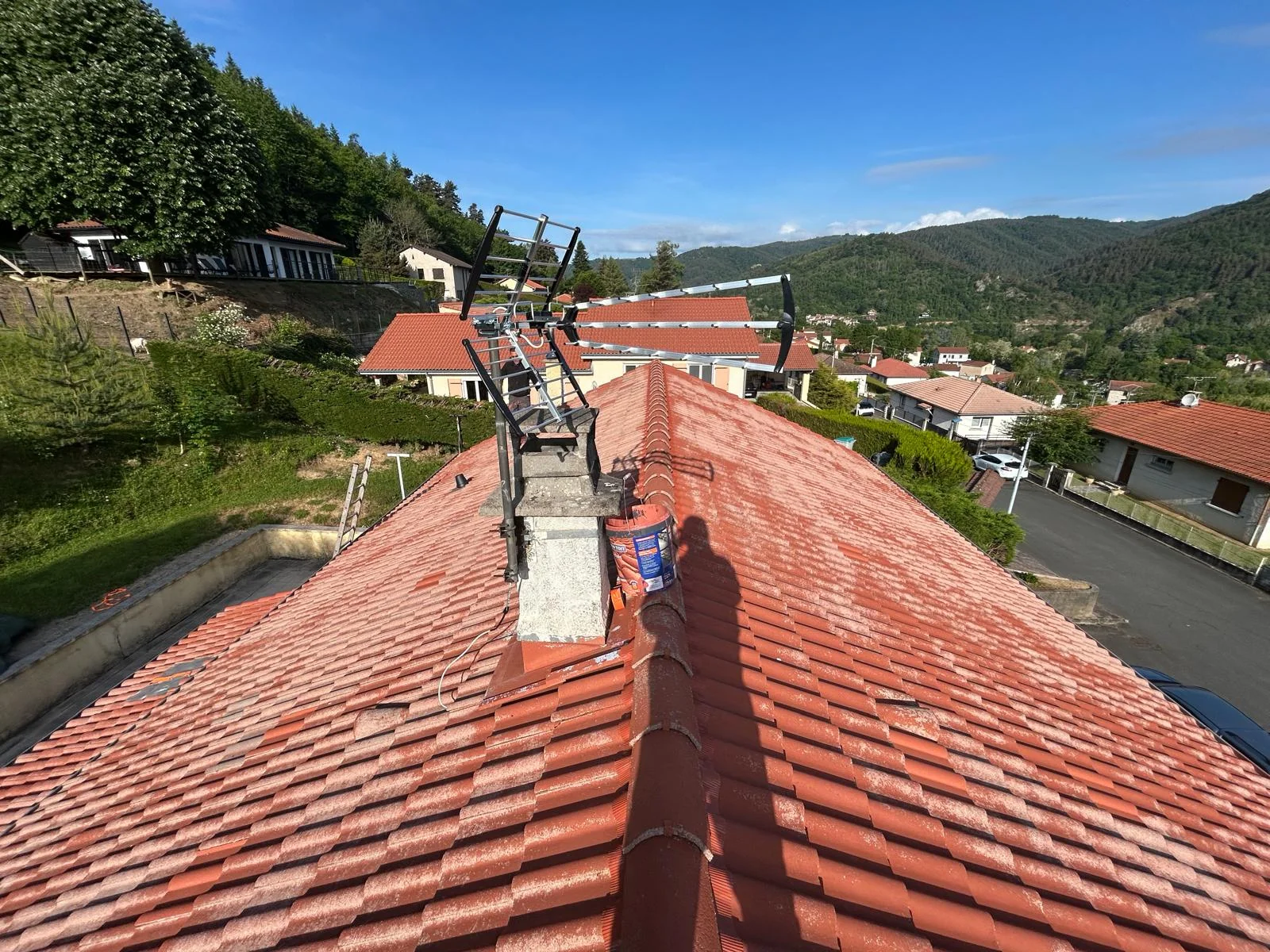 Toiture en tuiles rouges avec des dépôts clairs, cheminée et antenne