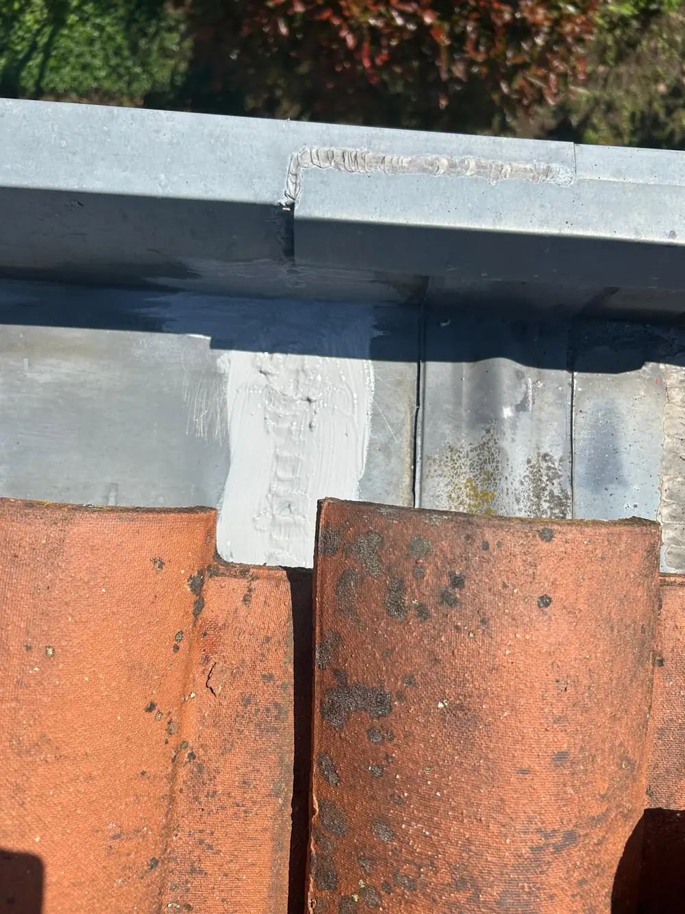 Jonction de chéneau en zinc soudée, avec un cordon d’étanchéité appliqué sur le raccord contre les tuiles